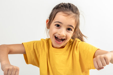 Little Caucasian girl driving invisible car isolated on white background.の写真素材
