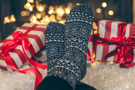 Feet in Christmas socks and gift boxes in front of the fireplace, close up.の写真素材