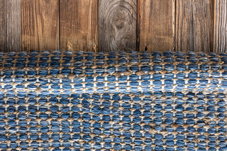 Hand woven geometric denim area rug on wooden floor.の写真素材
