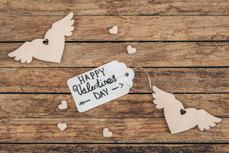 Hearts and gift tag with Happy Valentines Day inscription on wooden background.の写真素材