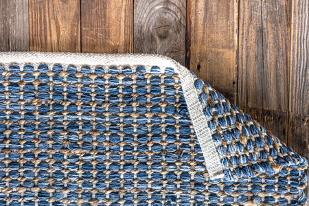 Hand woven geometric denim area rug on wooden floor.の写真素材