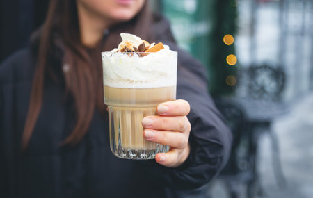 Coffee with cream, cinnamon and star anise in female hands outside.の写真素材