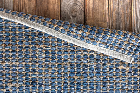 Hand woven geometric denim area rug on wooden floor.の写真素材