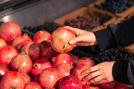 A woman chooses pomegranate fruit at a grocery store.の写真素材