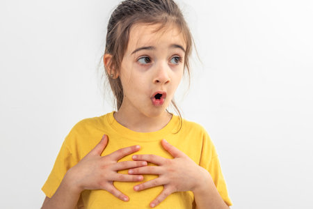 Little girl looks to the side in surprise on a white background isolated.の写真素材