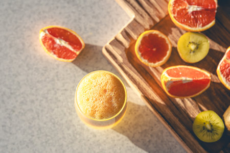 Freshly squeezed juice in a glass and fresh fruit on the kitchen table.の写真素材