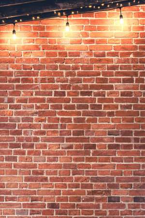 Lights garlands hanging from red brick wall at evening.の写真素材