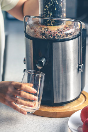 A woman makes apple juice at home with a juicer.の写真素材