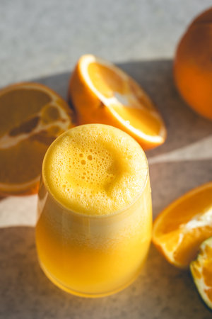Close-up, glass of orange juice on a blurred background with oranges.