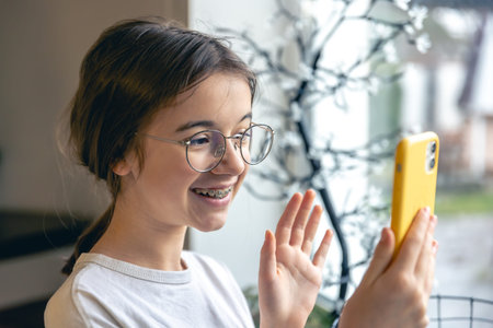 A teenage girl in glasses and braces communicates via video call.