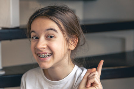 A teenage girl with braces smiles at home, showing her teeth.の写真素材