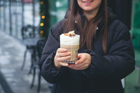 Coffee with cream, cinnamon and star anise in female hands outside.の写真素材