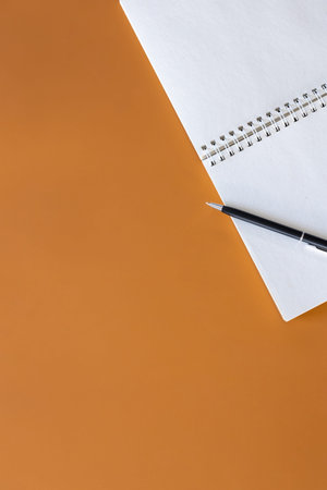 Open blank notepad on brown background, flat lay.