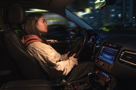Attractive young woman driving a car at night.