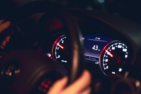 Drivers hands on the steering wheel of a car at night, night driving.