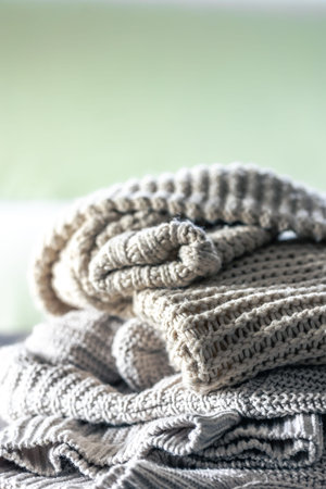 Stack of cozy knitted sweaters on wooden background.