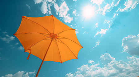 Orange umbrella outdoors with sunny blue sky, copy space.の素材