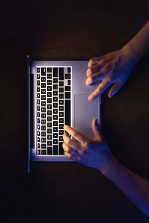 A male hands working on the laptop at night, top view.の写真素材