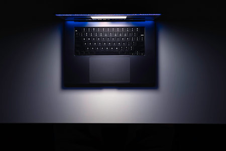 Top view of a laptop on a table, glowing screen in the dark.