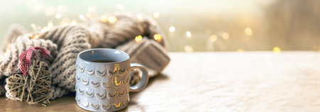 Close-up, shiny gray cup on a blurred background with a knitted element.