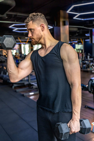 Athlete swings triceps with dumbbells in the gym. Healthy sports lifestyle.