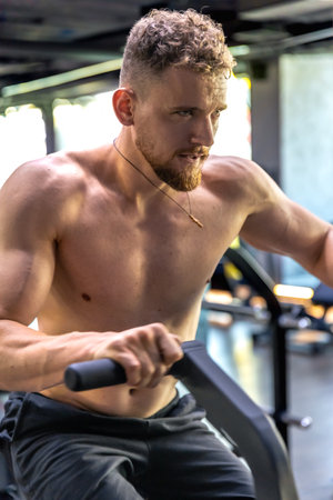 Athlete doing exercises on an air bike exercise bike close-up.の写真素材