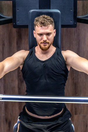 An athlete in the gym swings triceps with a barbell. Sports lifestyle.の写真素材