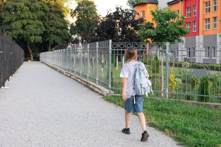 Schoolgirl walks near school. A girl with a backpack on her shoulders. Back view.の写真素材