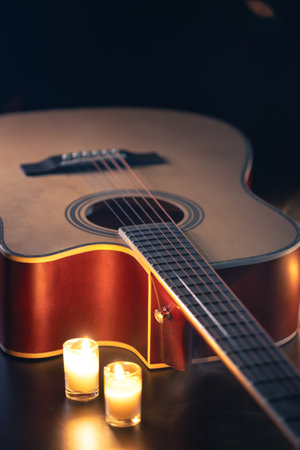 Acoustic guitar on a black background with candles.の写真素材