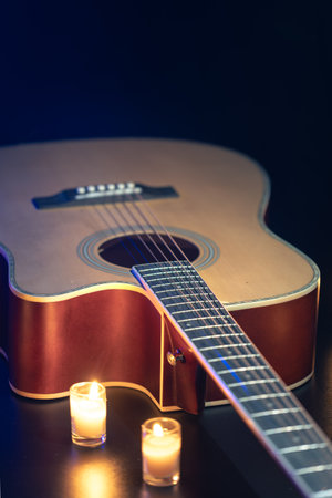 Acoustic guitar on a black background with candles.の写真素材