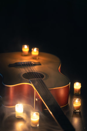Acoustic guitar on a black background with candles.の写真素材