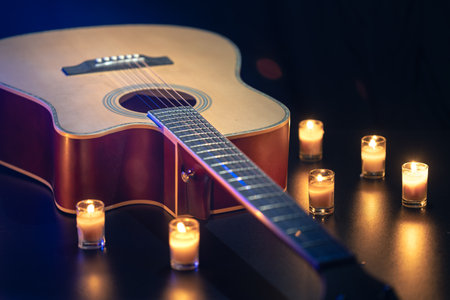 Acoustic guitar on a black background with candles.の写真素材