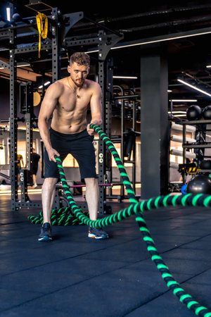 Ahlete performs triceps exercises with cross fit rope. Sports lifestyle.の写真素材
