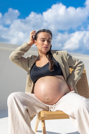 Stylish pregnant woman on a beautiful wicker chair. On a light background.の写真素材