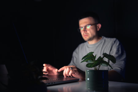 Young man works at the computer at night.の写真素材