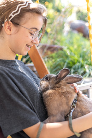 A girl plays with a domestic rabbit on the street. Pet concept.の写真素材