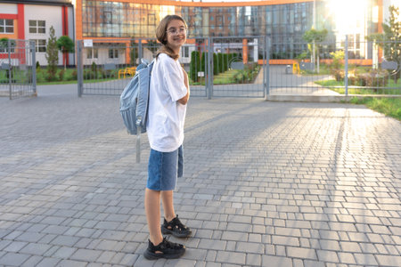 Schoolgirl with a backpack on her shoulders. School on the background of the sunset. Back to school.の写真素材