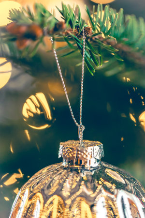 Silver shiny Christmas ball on a Christmas tree branch, close-up.の写真素材
