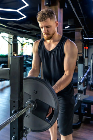 An athlete in the gym swings triceps with a barbell. Sports lifestyle.の写真素材
