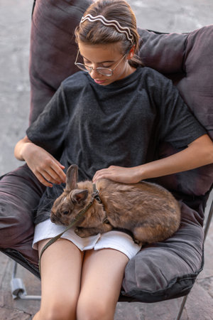 A girl plays with a domestic rabbit on the street. Pet concept.の写真素材