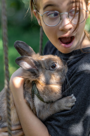 A girl plays with a domestic rabbit on the street. Pet concept.の写真素材