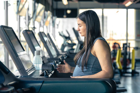 Pregnant woman on a treadmill in the gym. Healthy sports lifestyle.の写真素材