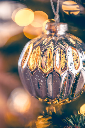 Silver shiny Christmas ball on a Christmas tree branch, close-up.の写真素材