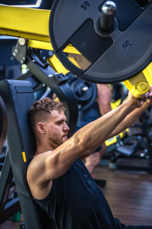 An athlete in the gym swings triceps with a barbell. Sports lifestyle.の写真素材