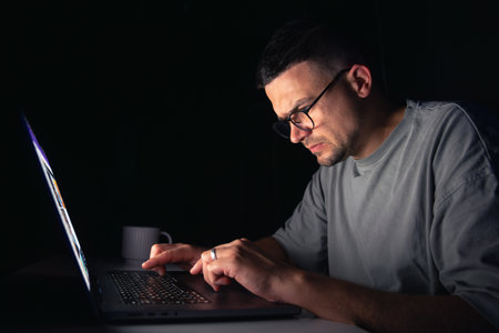 Young man works at the computer at night.の写真素材