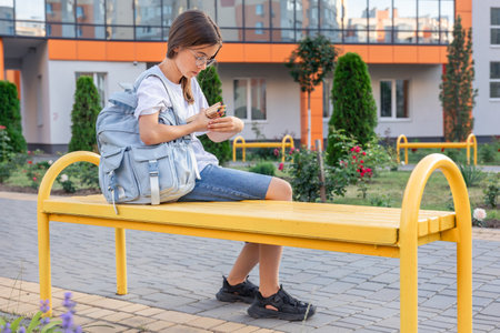 The student is sitting on a bench with pencils. A girl with a backpack. Girl with school supplies.の写真素材