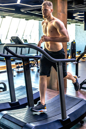 Athlete on a treadmill in the gym. Shirtless man in the gym. Sports lifestyle.の写真素材