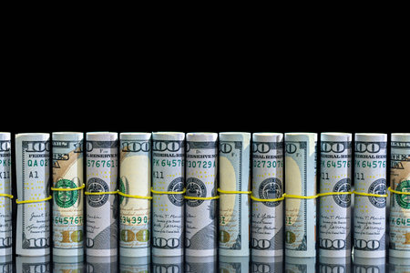 Twisted 100 dollar bills on a black background. Finance concept background.の写真素材