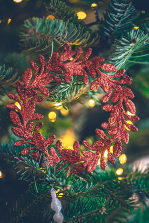 Decorative red wreath on a Christmas tree with bokeh lights.の写真素材