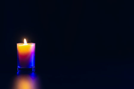 Burning candle on black background with backlight. Memorial Day.の写真素材